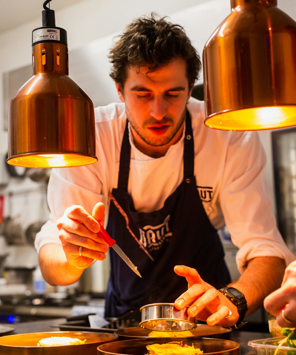 Chef plating a dish under warm kitchen lamps