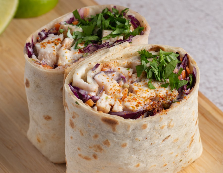 Chicken shawarma roll cut in half on a wooden board